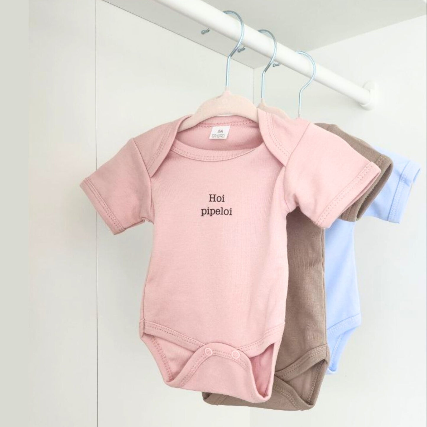 Body's voor baby's in drie kleuren: roze, beige en blauw. Er staat 'hoi pipeloi' op geschreven. Dit is een origineel cadeau voor baby's