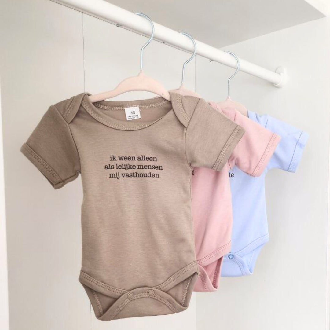 Drie babybody's die in de kleerkast hangen. De body's hebben een grappig opschrift